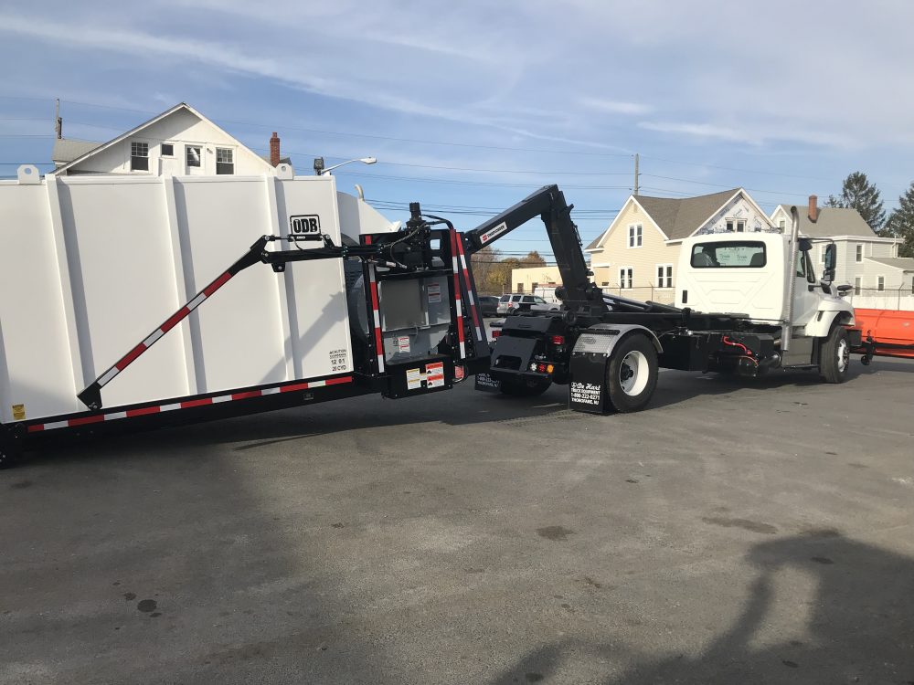 Right side view of white hooklift truck in parking lot