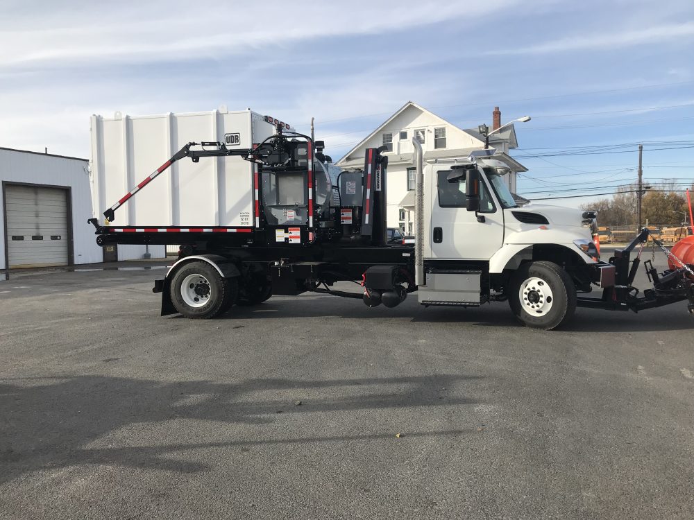 Side view of white hooklift truck in parking lot
